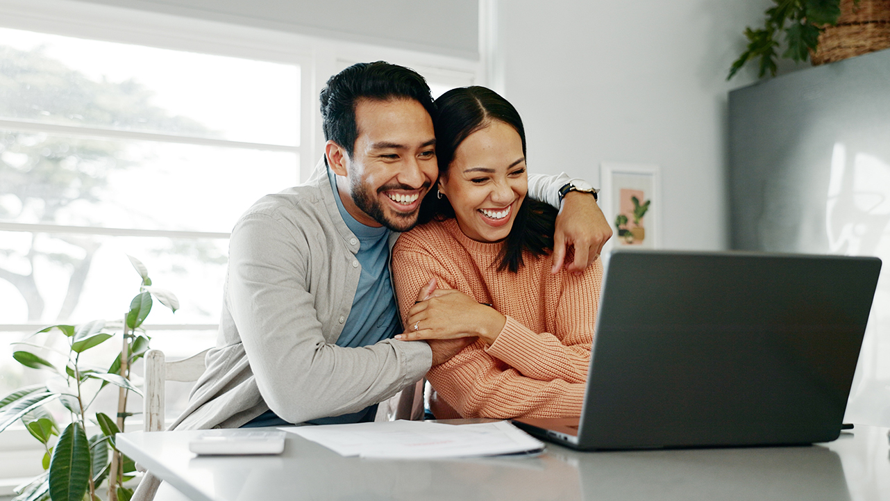 A happy couple looking at a laptop together, reviewing home upgrade options.