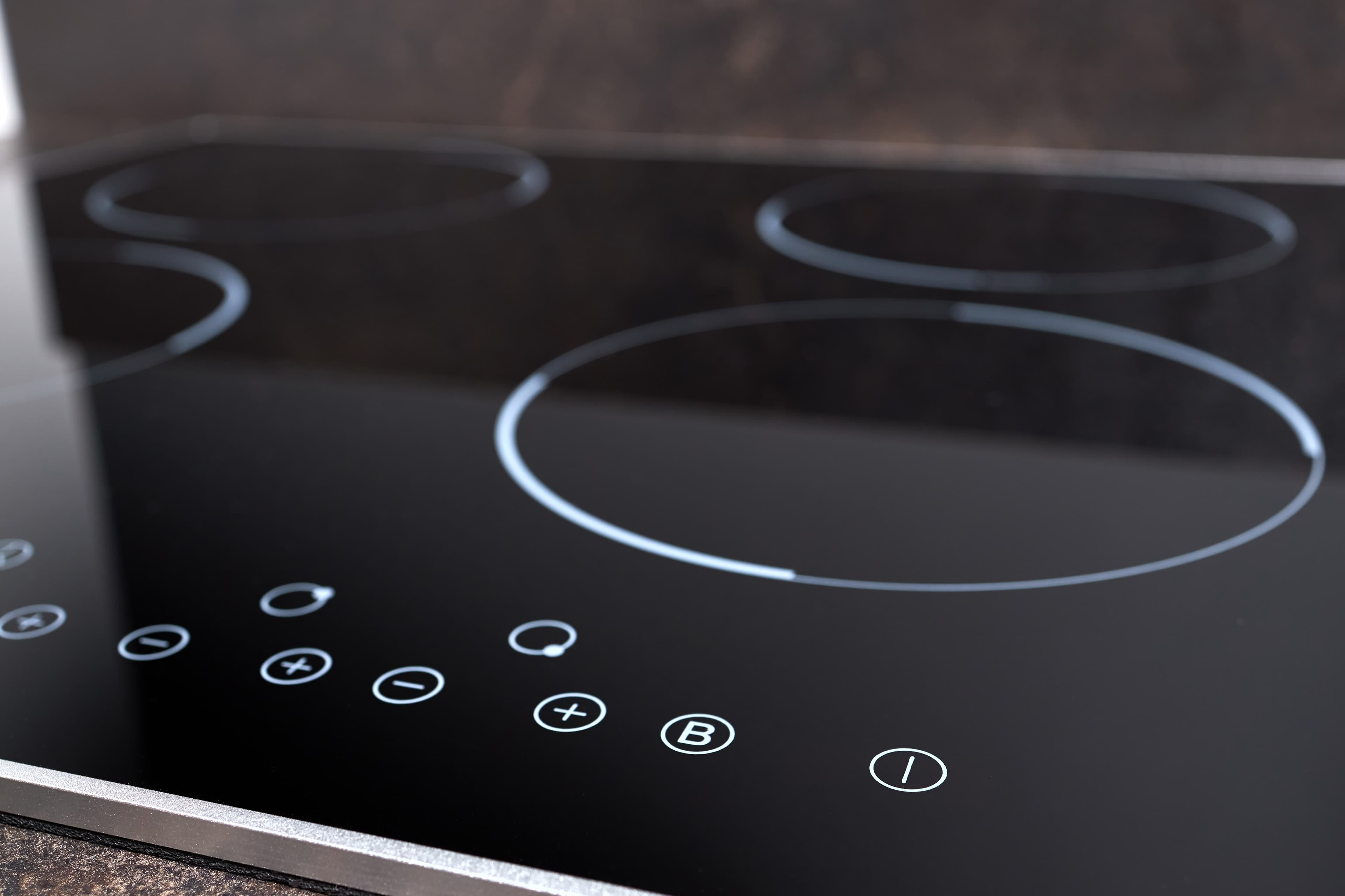 Close-up of a sleek black induction cooktop with touch controls.
